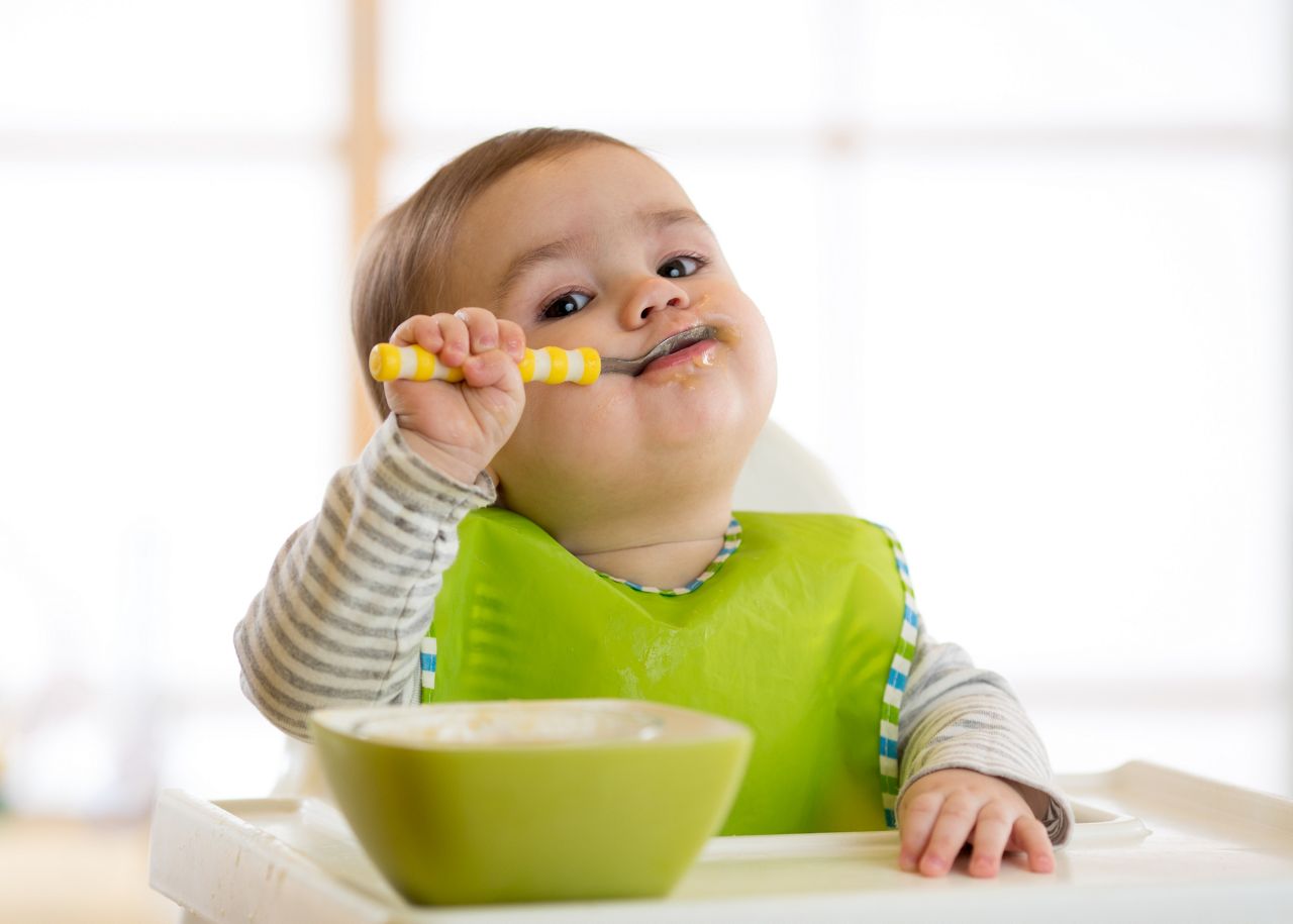Happy infant baby boy spoon eats itself; Shutterstock ID 631322687; purchase_order: 25 thumbnail photos ; job: ; client: ; other: 