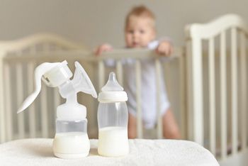 Manual breast pump and bottle with breast milk on the background of little baby in bed.; Shutterstock ID 759177826; purchase_order: DNC Thumbnails; job: Infographics; client: ; other: Replacements