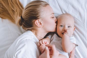 top view of mother kissing her infant baby in bed; Shutterstock ID 791332813; purchase_order: DNC Thumbnails; job: Webinars 1 (50/189); client: ; other: 