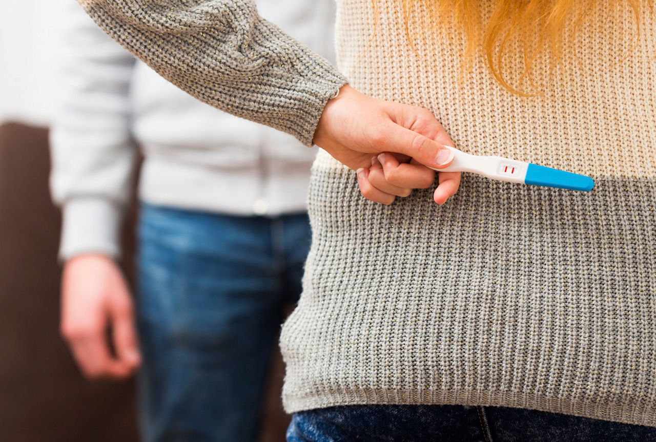 Close-up of a woman holding positive pregnancy test, waiting to surprise her lover.