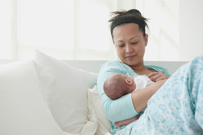 asian mum cudding baby in bed