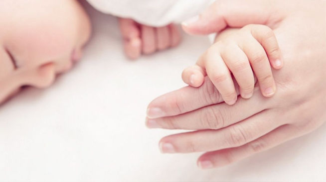 sleeping baby holding mums hand