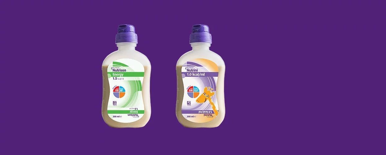 Zwei Nutricia-Trinknahrungsflaschen auf lila Hintergrund, links Nutrilson Energy, rechts Nutrini mit Tiermotiv-Etikett.
