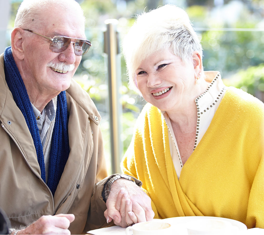 Senior couple holding hands sitting at a table