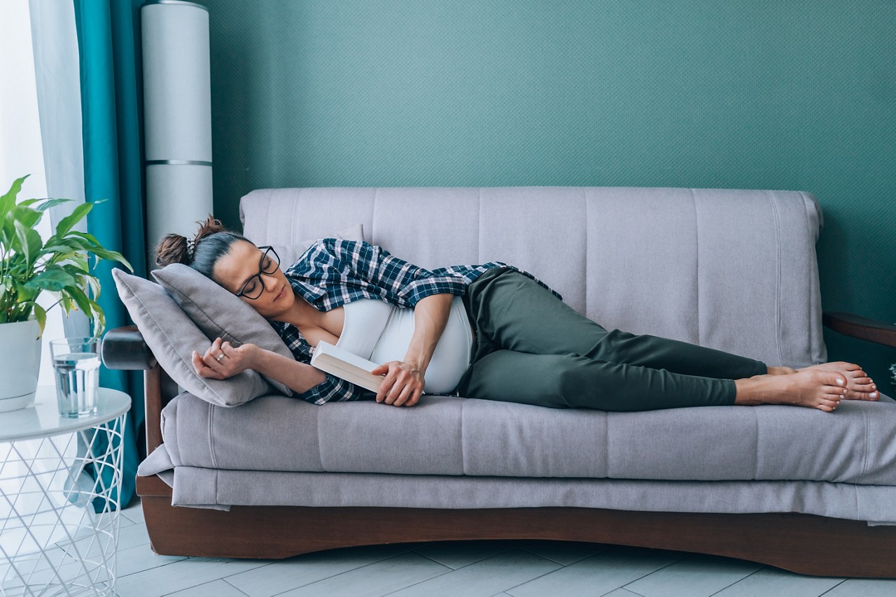 Pregnant woman in bed at home at home holding hands on stomach