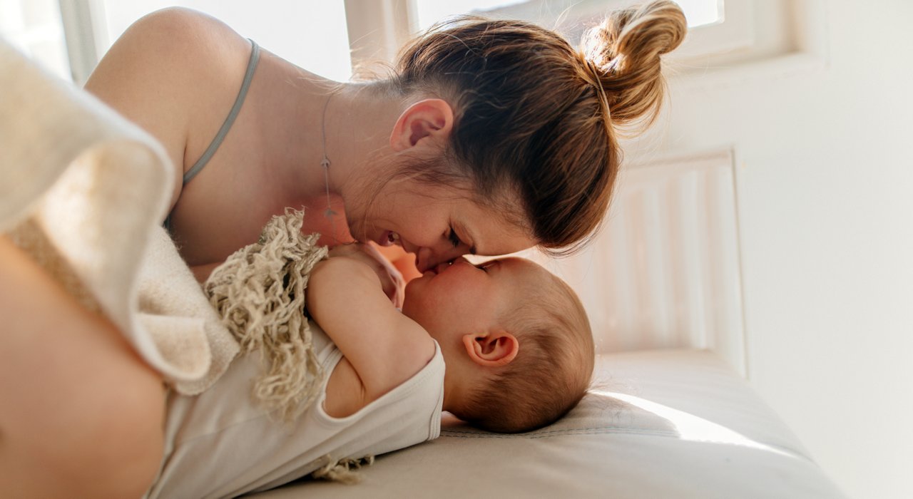 Mom and baby boy cuddling on the bed in the morning