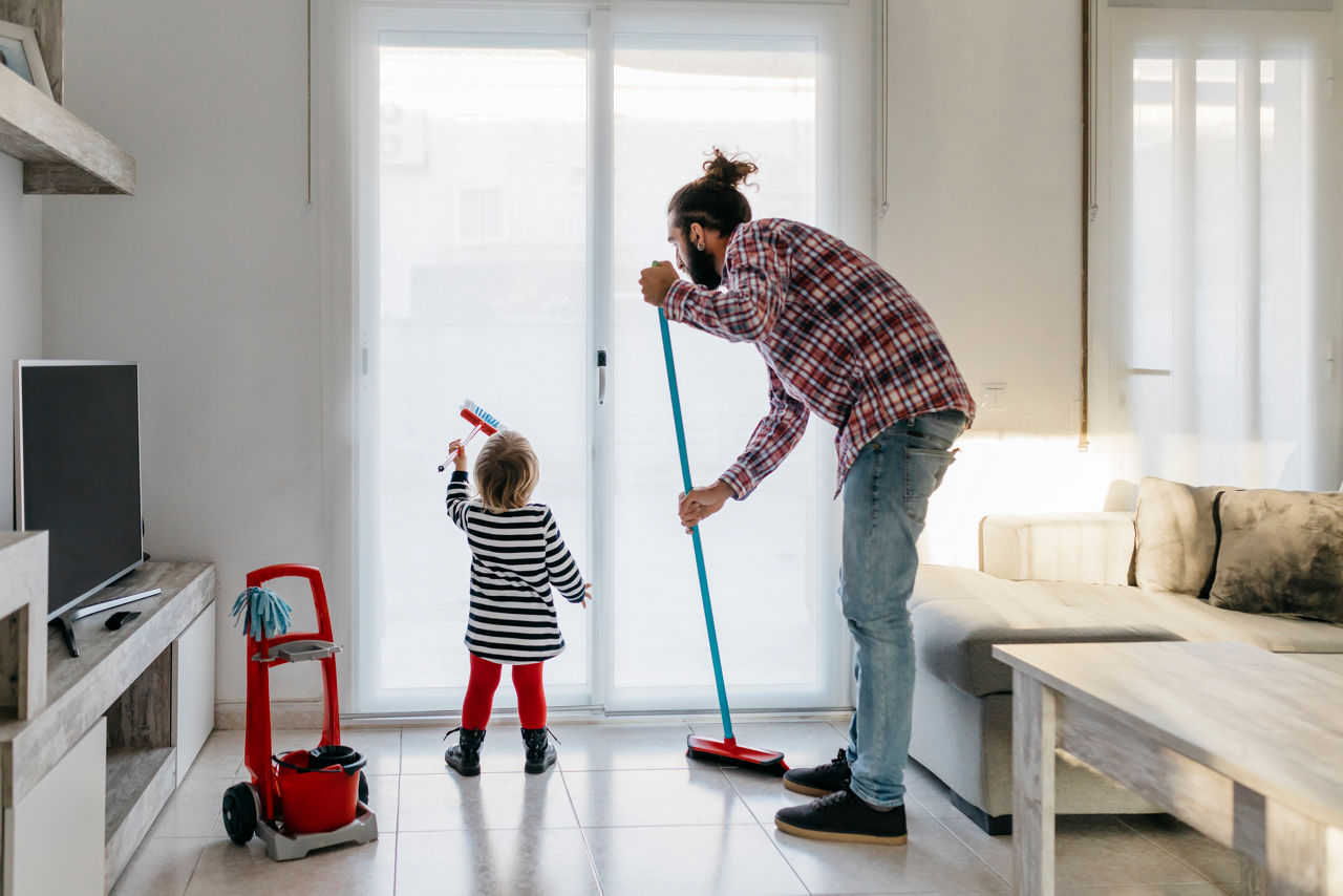 Father and little daughter cleaning the living room together