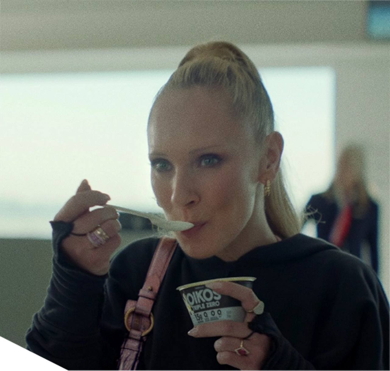 Woman holding Oikos yogurt cup indoors
