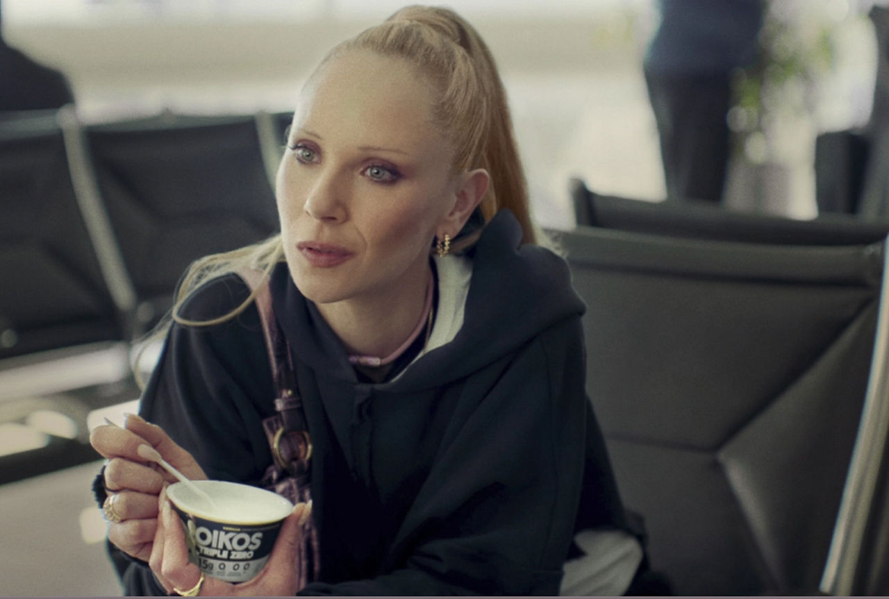 Woman holding Oikos yogurt in airport lounge