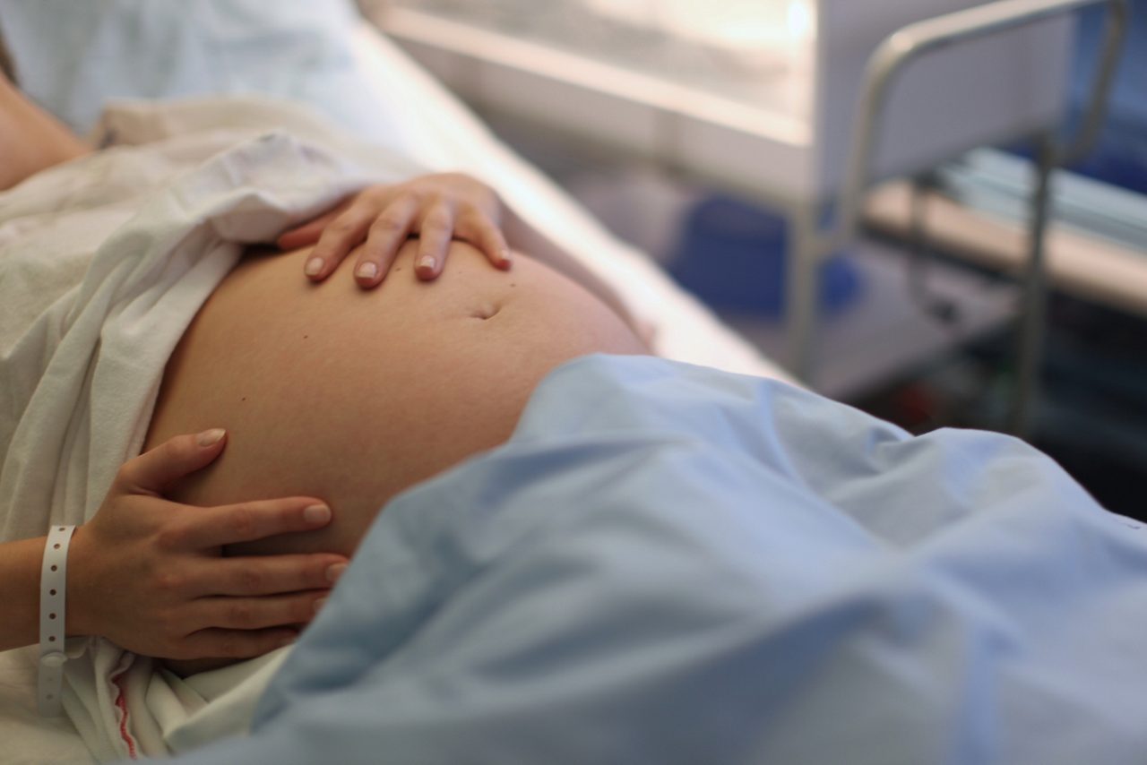 Schwangere hält Babybauch im Kreissaal