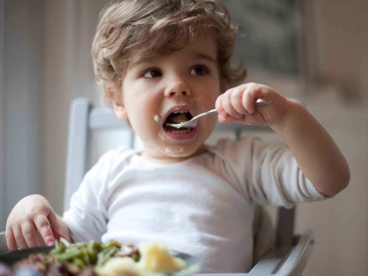 toddler eating roast dinner with fork