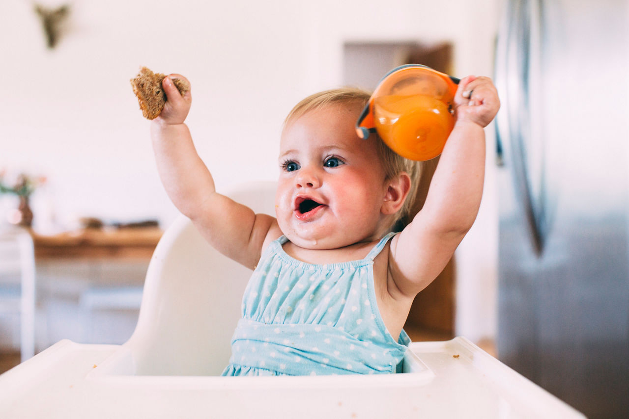 Toddler holding beaker in air