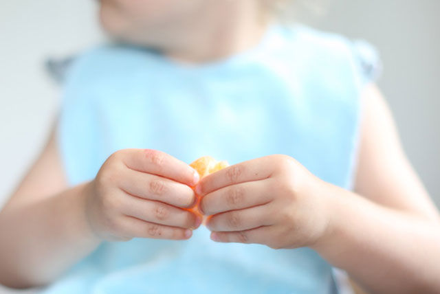 toddler holding orange slice