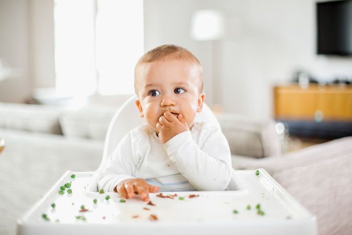 toddler-sitting-in-high-chair-eating-food