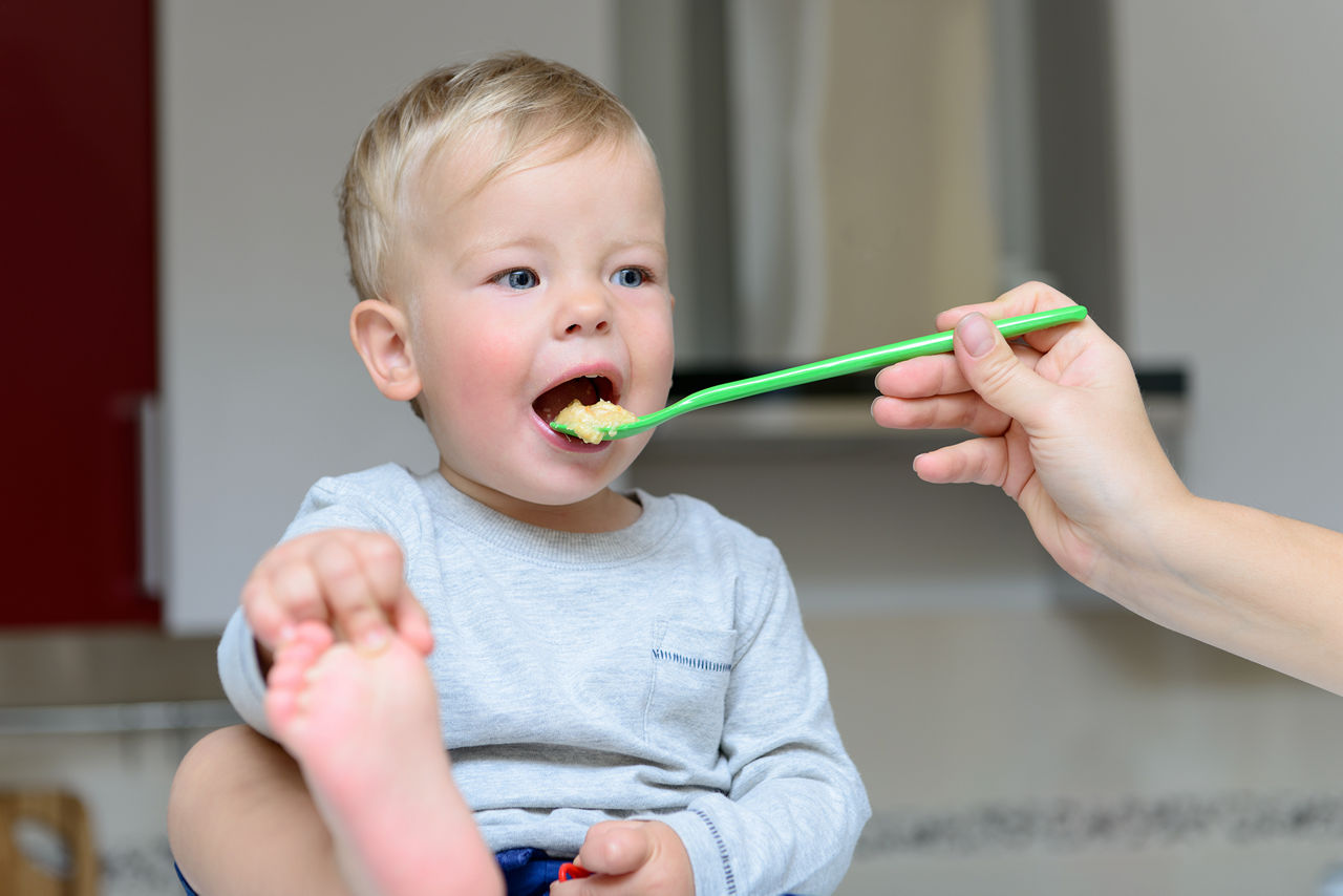 Toddler Happily Spoon Feeding