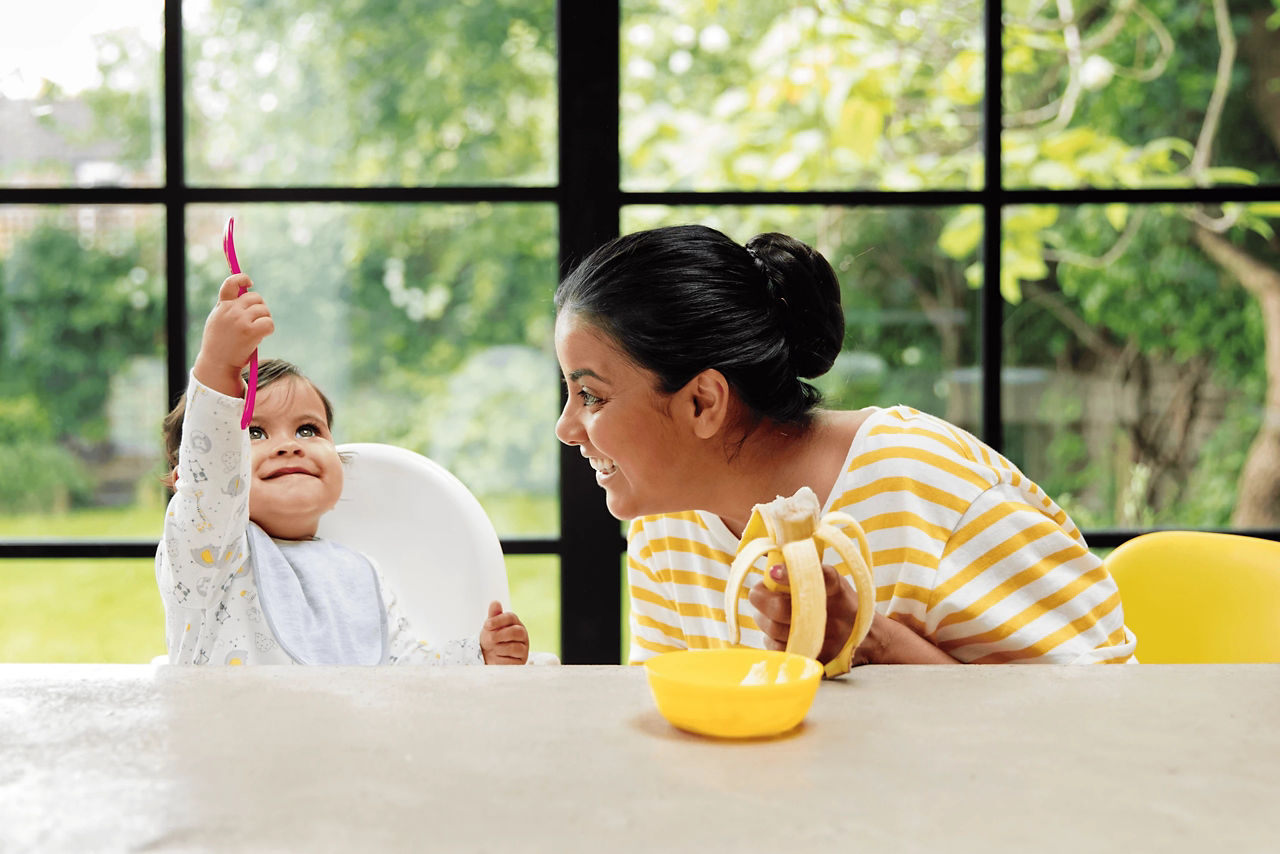 Toddler eating with mom banana puree