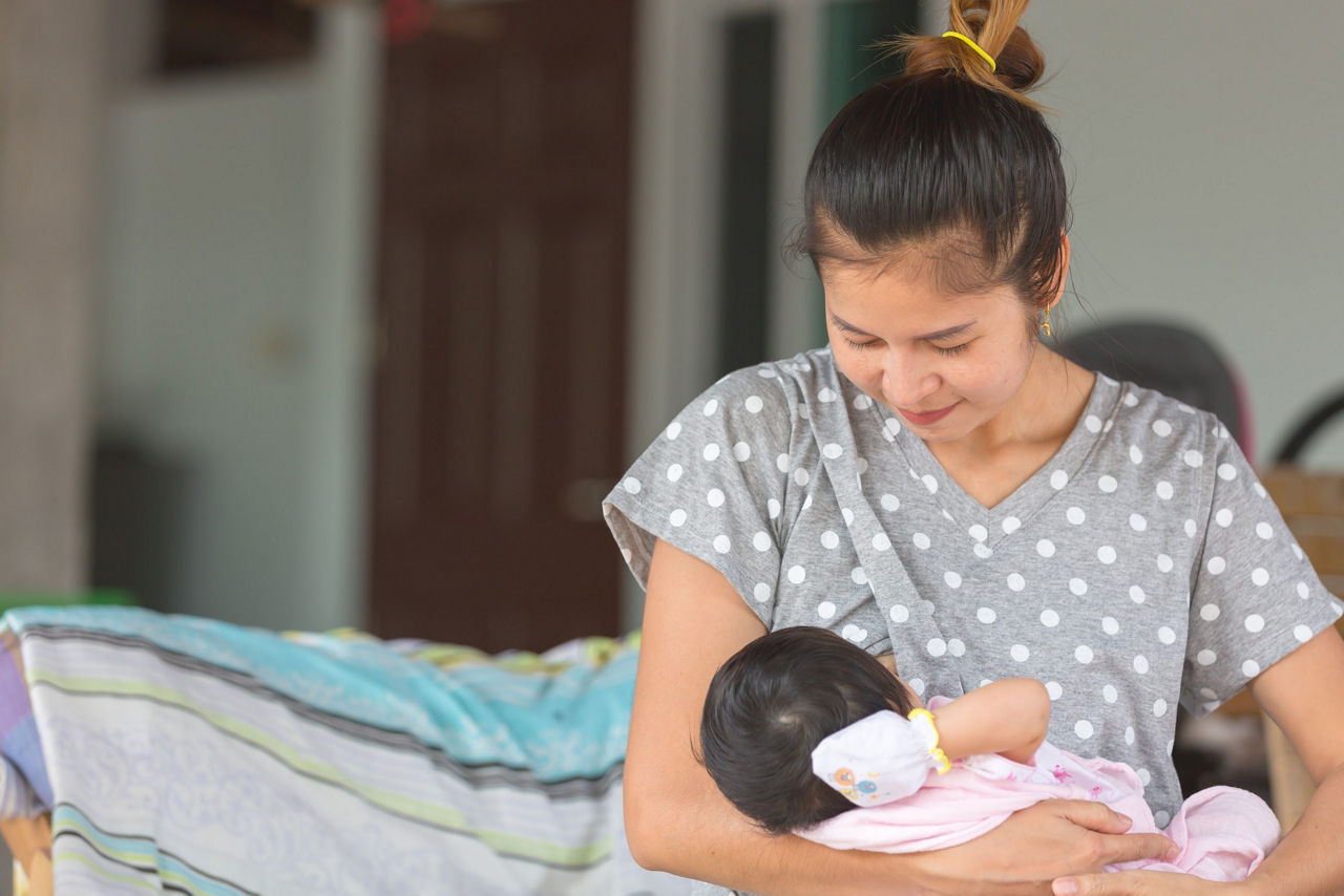 Đặt bé nằm bú thoải mái là một trong những cách phòng ngừa bé sơ sinh sặc sữa và thở khò khè