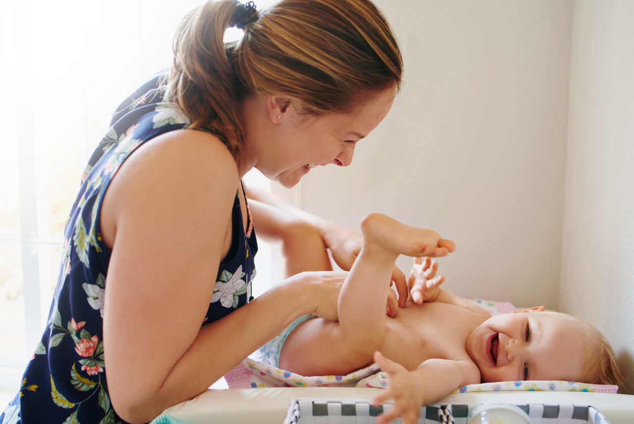 Shot of a young woman changing her adorable baby girlâ  s diaper on a table at home