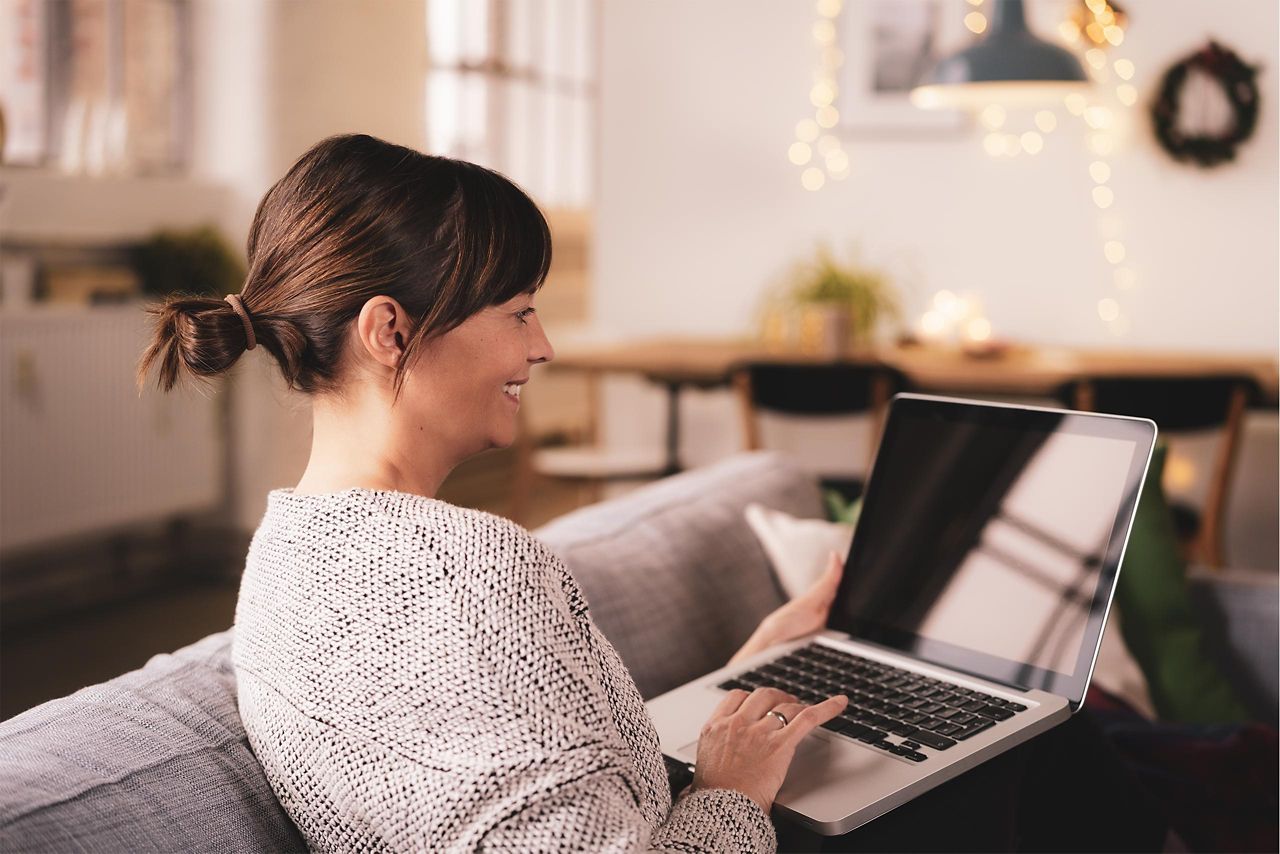 Frau arbeitet am Laptop auf der Couch