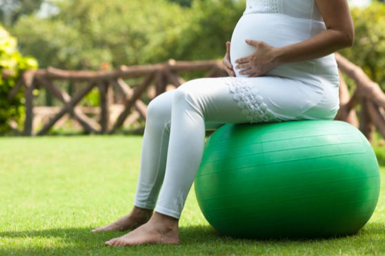 Young pregnant woman sitting on fitness ball