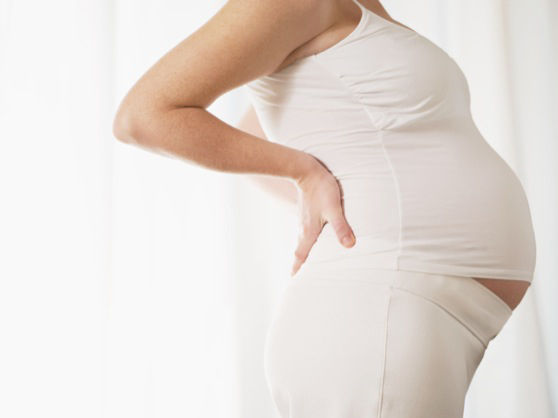 Cropped view of italian 7 months pregnant woman massaging her back. Horizontal shape, side view, copy space