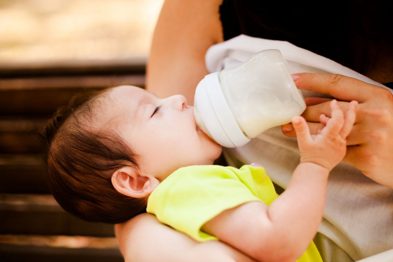 The image of the woman feeding her newborn baby from a children's small bottle; Shutterstock ID 216600691,woman bottlefeeding her newborn baby