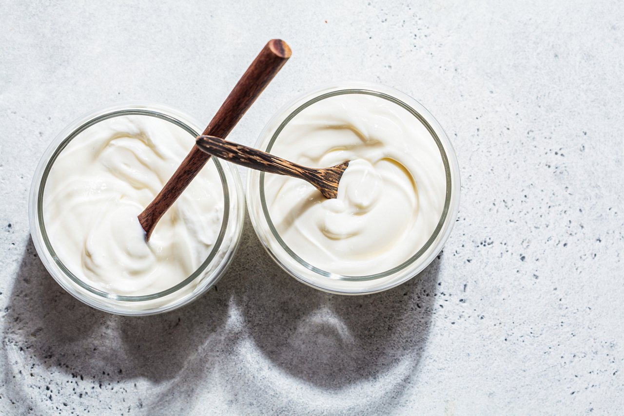 Homemade yogurt in glass jars, light background, copy space. Yoghurt preparation concept.