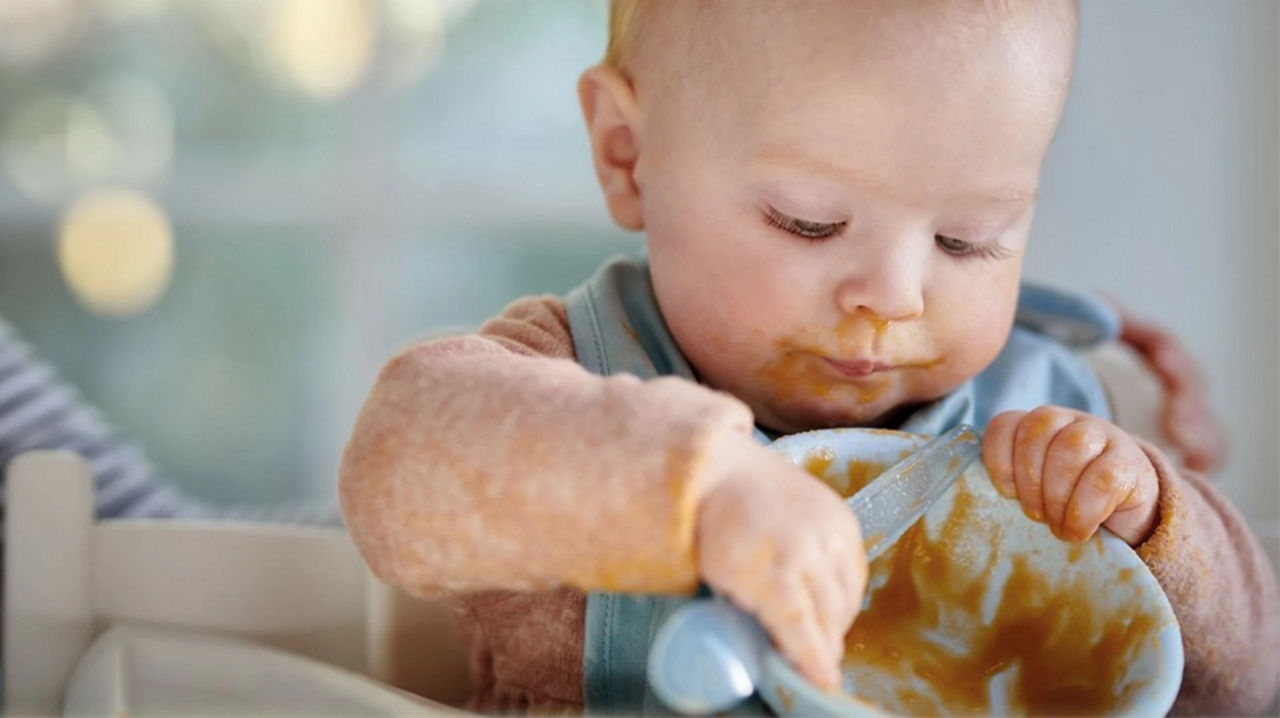 Baby holding bowl of food