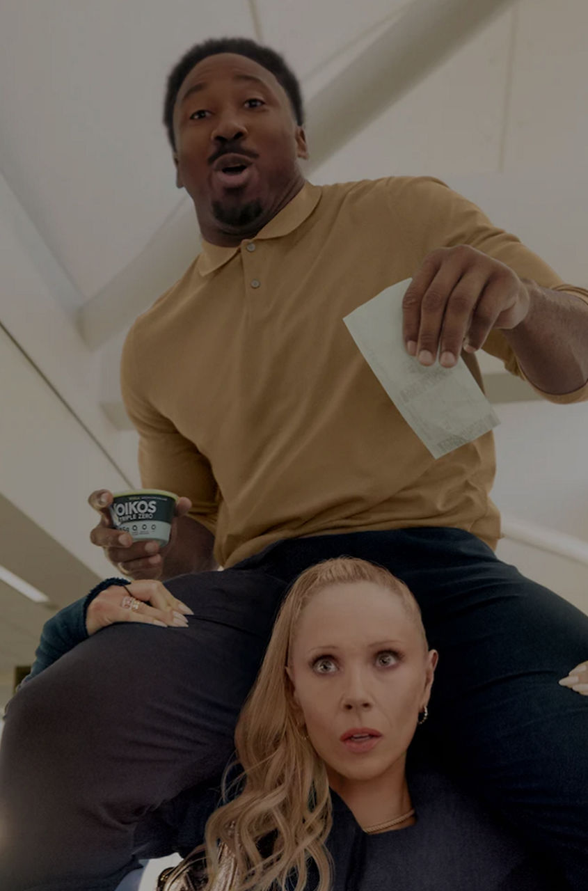 Juno Temple runs in airport, Myles Garrett on shoulders, clutching pass and Oikos Triple Zero cup