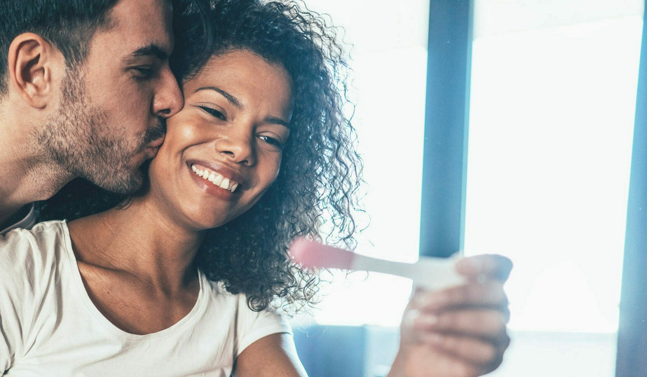 Happy Couple with Positive Pregnancy Test in the bed at home