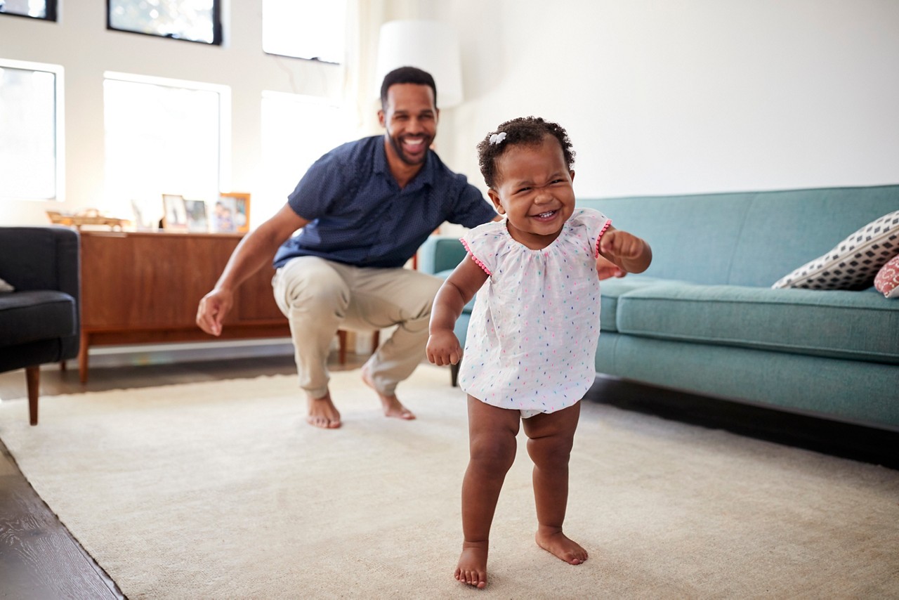 Baby Daughter Dancing With Father In Lounge At Home