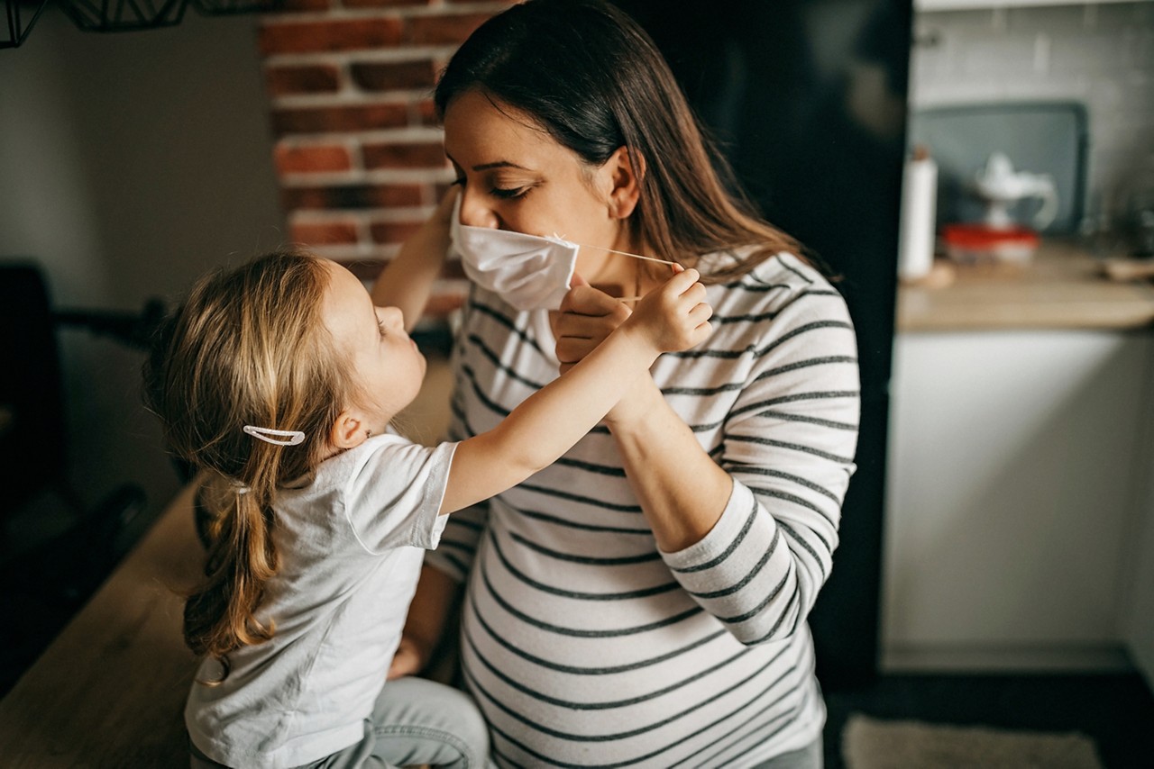 Mother and daughter eating fruits to get vitamins to survive the virus. Wearing n95 face mask