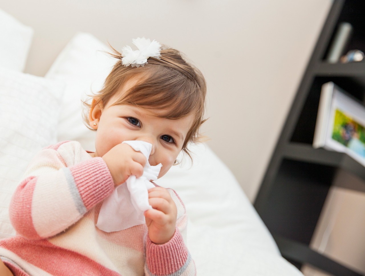 Little girl wiping her nose with a tissue