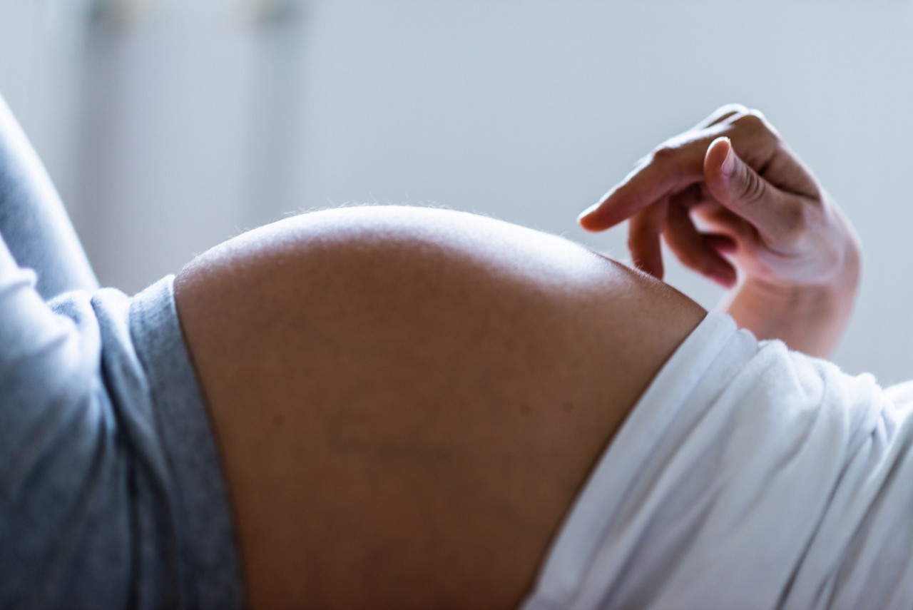Close-up of pregnant woman lying down and playing with belly.